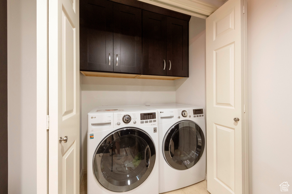 Washroom with cabinet space and washing machine and clothes dryer
