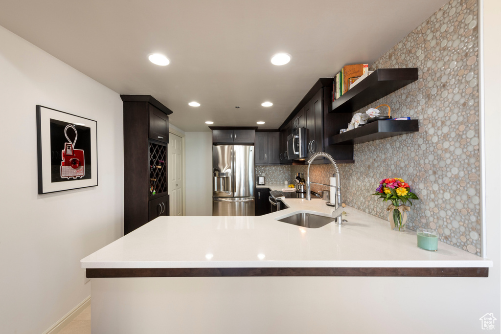 Kitchen featuring stainless steel appliances, light countertops, tasteful backsplash, a peninsula, and open shelves