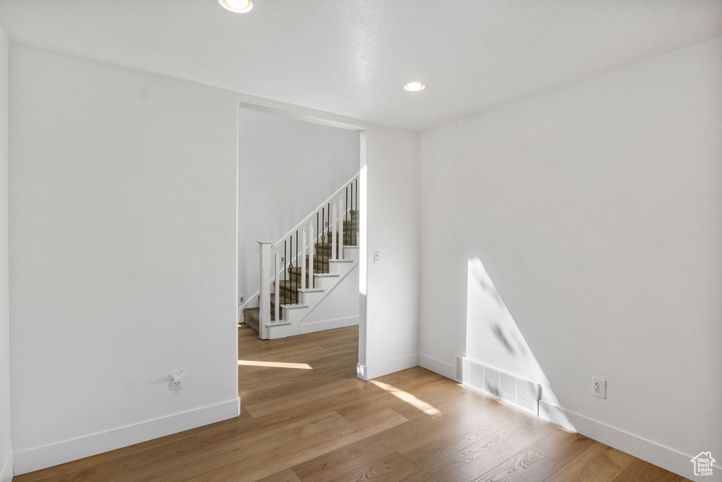 Unfurnished room featuring stairway, wood finished floors, and recessed lighting
