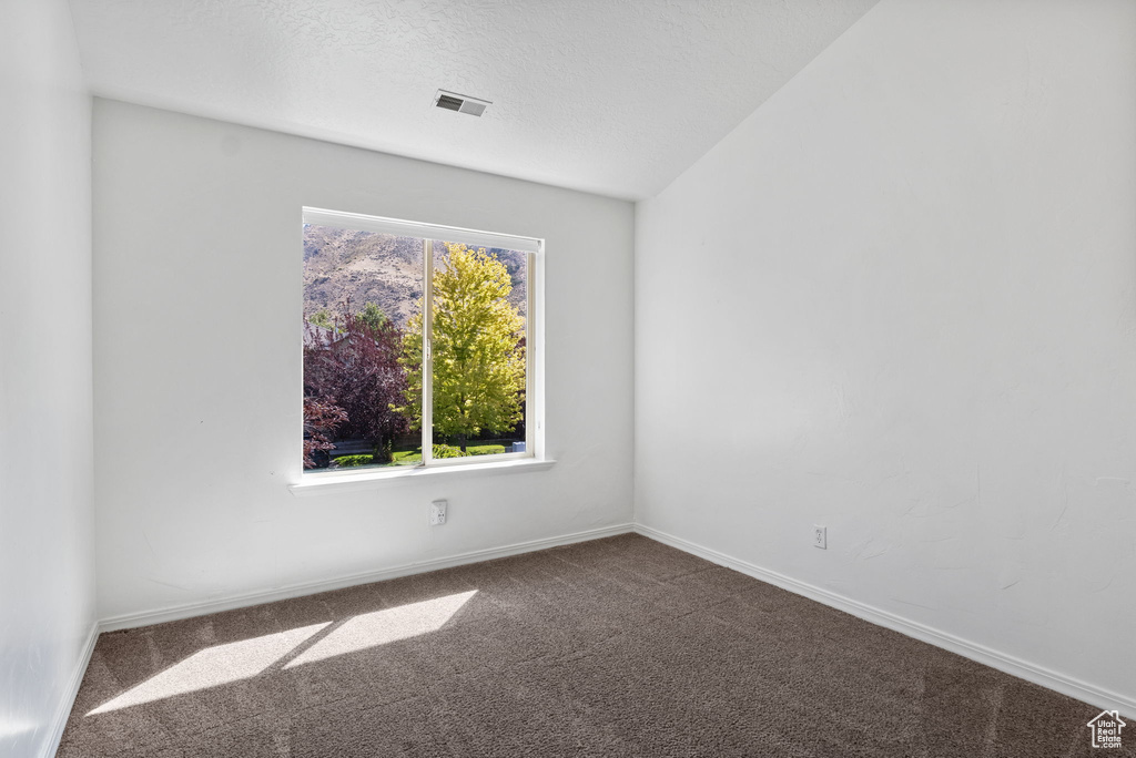 Carpeted spare room featuring baseboards