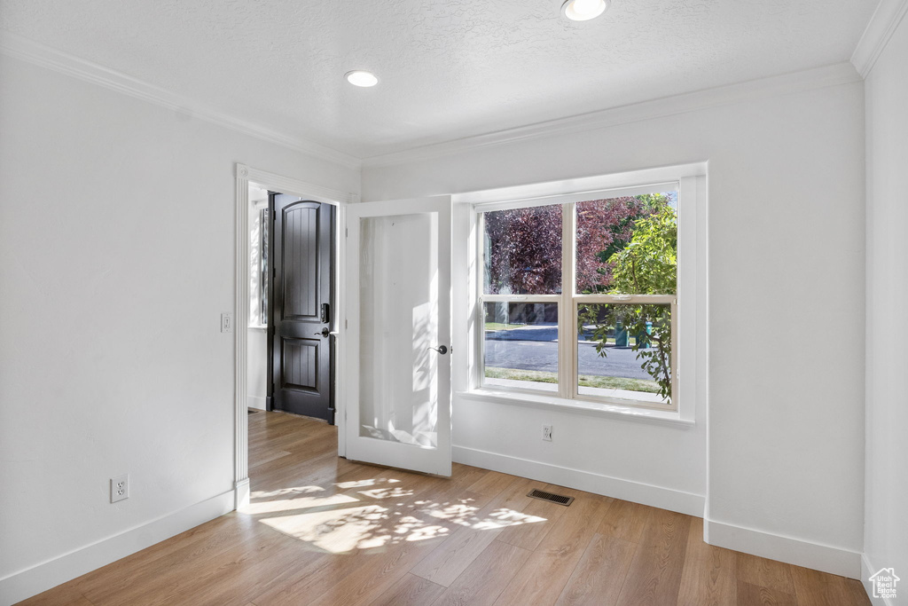 Unfurnished room featuring ornamental molding, light wood-type flooring, recessed lighting, and a textured ceiling