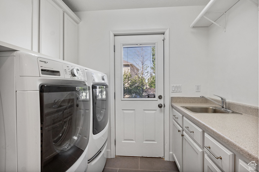 Washroom featuring washer and clothes dryer, cabinet space, and dark tile patterned flooring