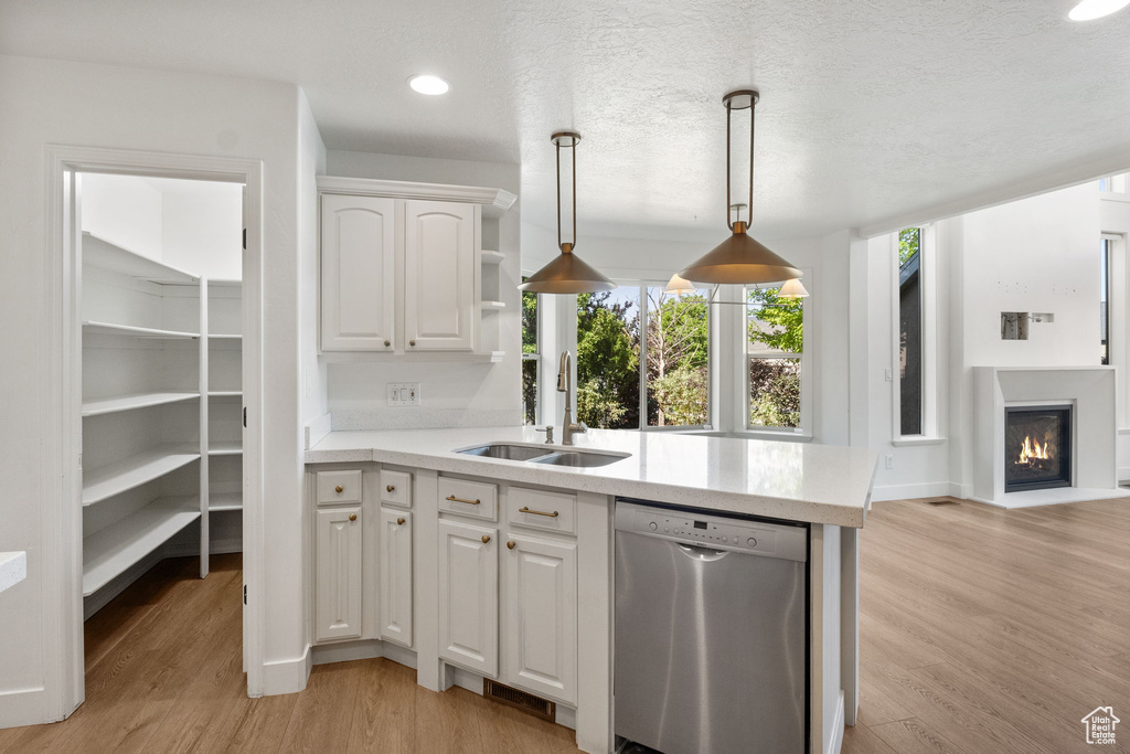 Kitchen with stainless steel dishwasher, light countertops, white cabinets, healthy amount of natural light, and recessed lighting