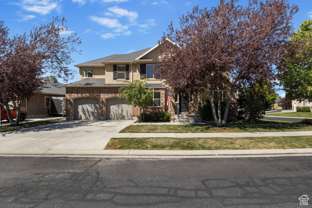 View of front of property featuring an attached garage, driveway, and stucco siding
