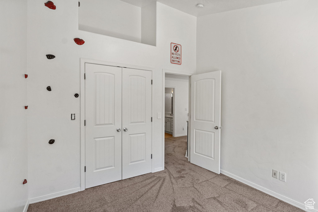 Unfurnished bedroom featuring carpet floors, a closet, and a high ceiling