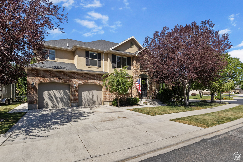 View of front of house with a garage, stucco siding, driveway, a shingled roof, and a front yard