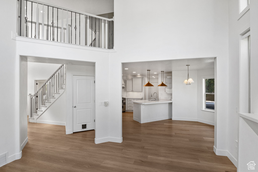 Unfurnished living room with a high ceiling, wood finished floors, and stairs