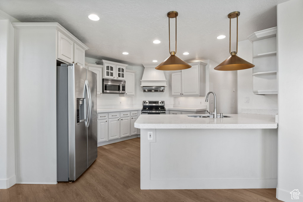 Kitchen with appliances with stainless steel finishes, custom range hood, open shelves, a peninsula, and recessed lighting