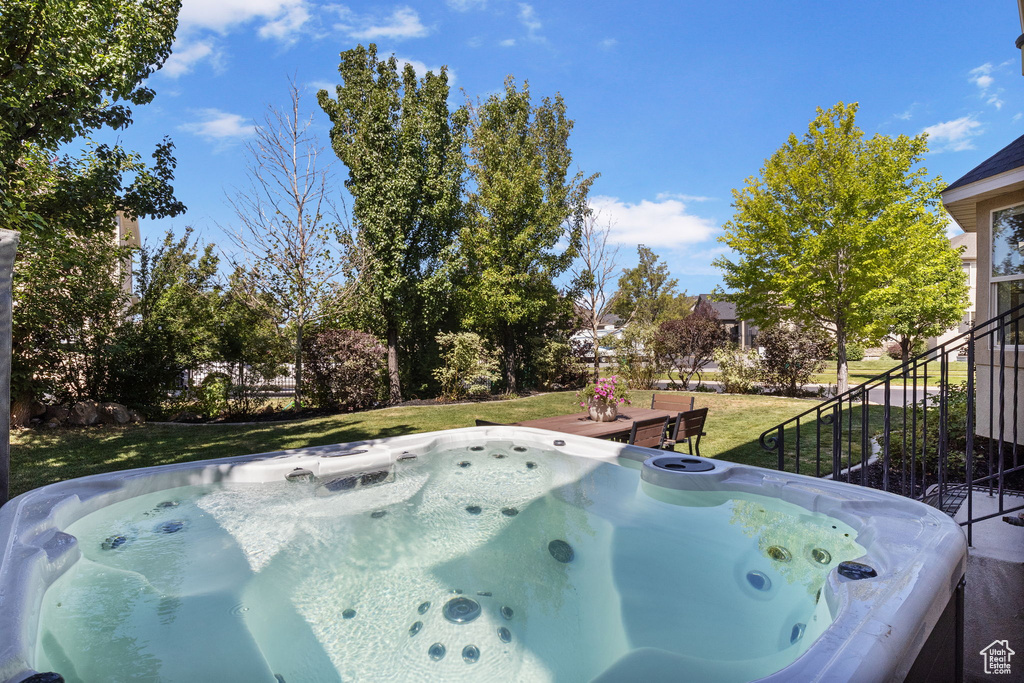 View of grassy yard with a hot tub