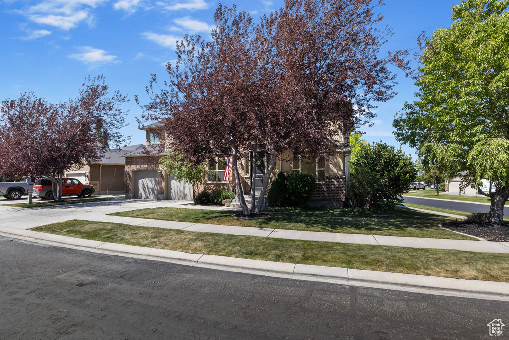 Obstructed view of property with brick siding, concrete driveway, a front lawn, and a garage