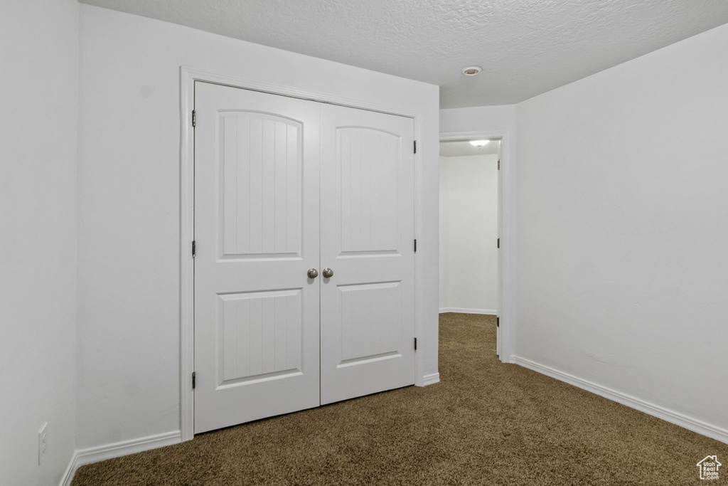 Unfurnished bedroom featuring carpet, a closet, and a textured ceiling