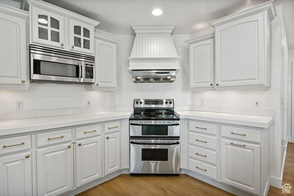 Kitchen featuring appliances with stainless steel finishes, white cabinetry, light wood finished floors, recessed lighting, and light countertops