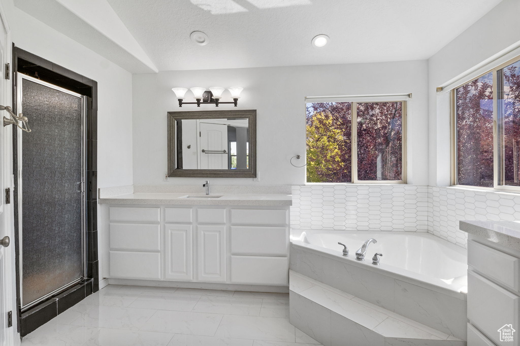 Bathroom with vanity, a bath, and a stall shower