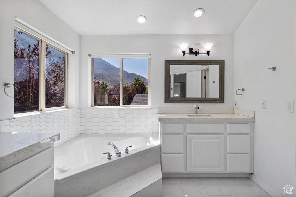 Full bathroom with vanity, marble finish flooring, a bath, and a mountain view
