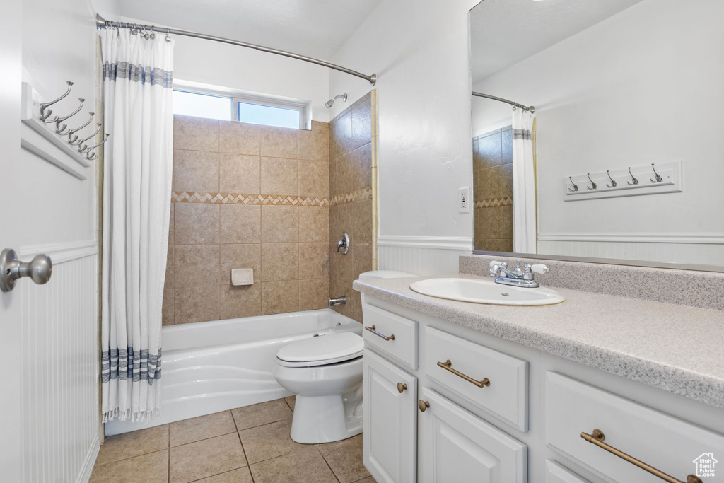 Full bathroom with shower / bathtub combination with curtain, vanity, tile patterned flooring, and wainscoting