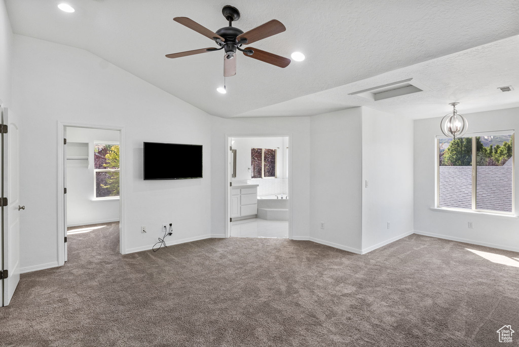 Unfurnished living room featuring carpet, healthy amount of natural light, lofted ceiling, a ceiling fan, and recessed lighting
