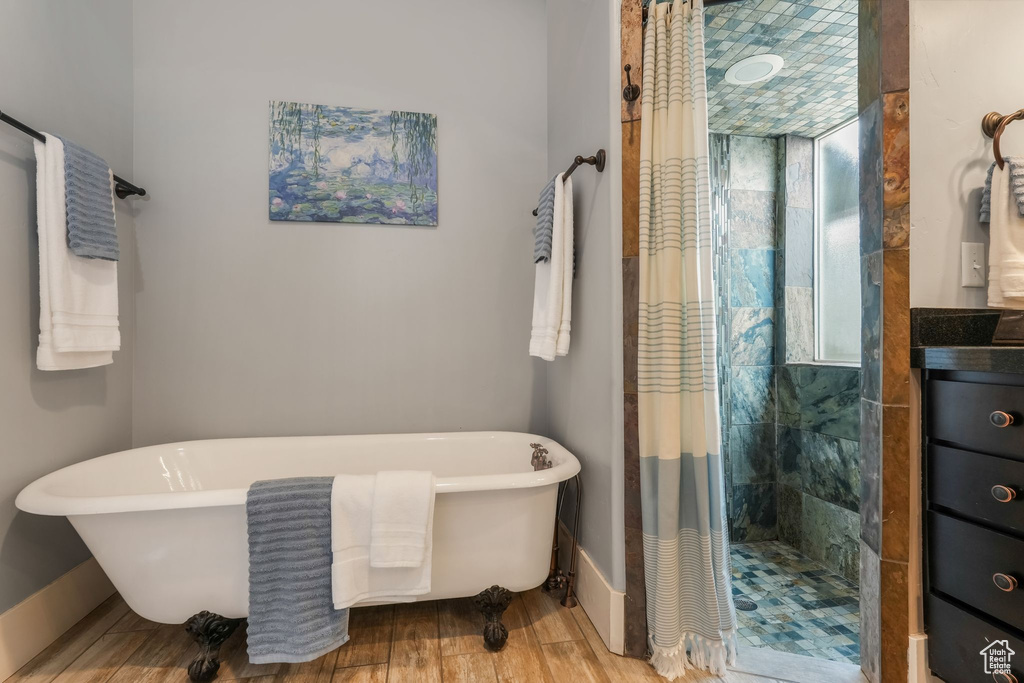 Full bathroom with tiled shower, a freestanding bath, and wood finished floors