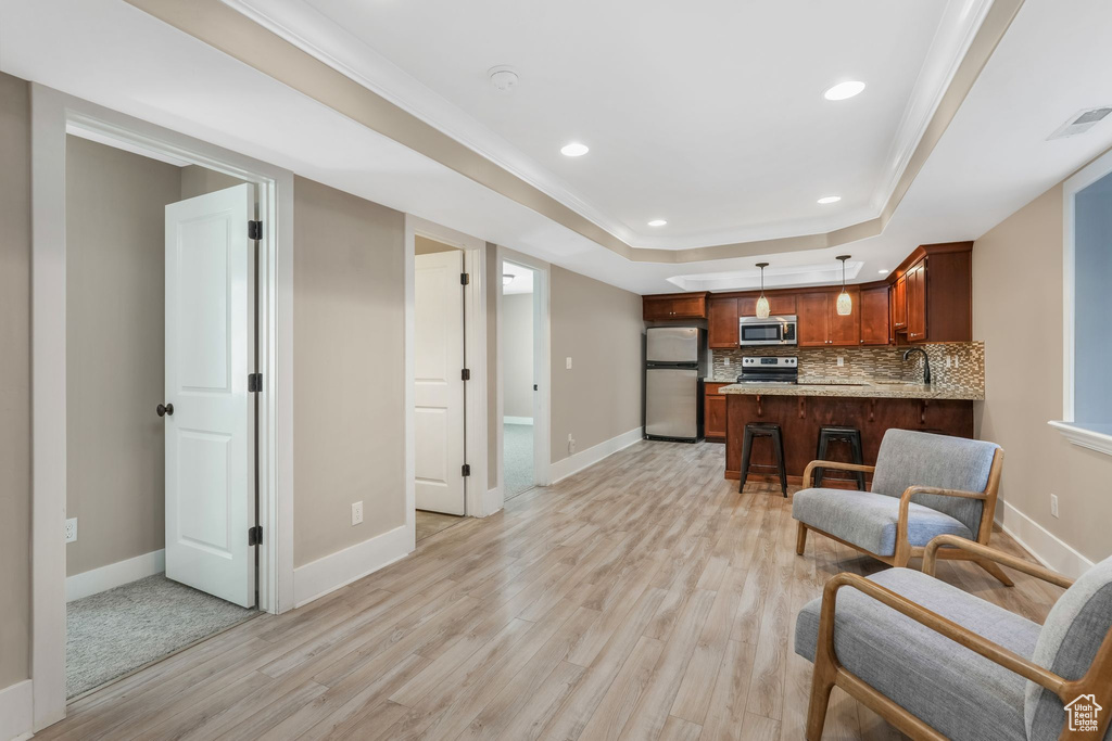 Living area featuring light wood finished floors, a tray ceiling, and recessed lighting