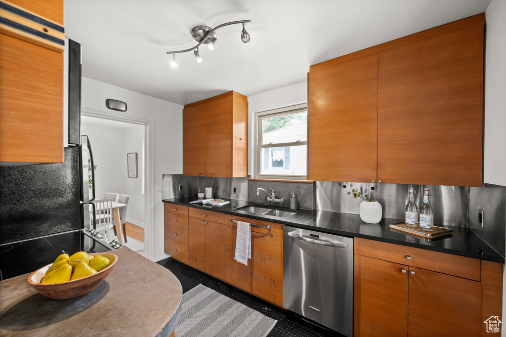 Kitchen featuring stainless steel dishwasher, backsplash, dark countertops, and brown cabinetry