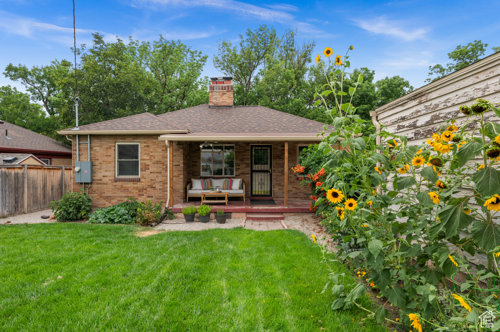 View of front facade featuring brick siding, a shingled roof, a chimney, and covered porch