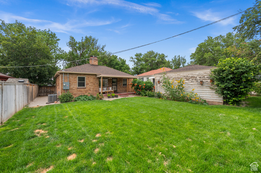 Rear view of house with a chimney, a fenced backyard, brick siding, a patio, and a shingled roof
