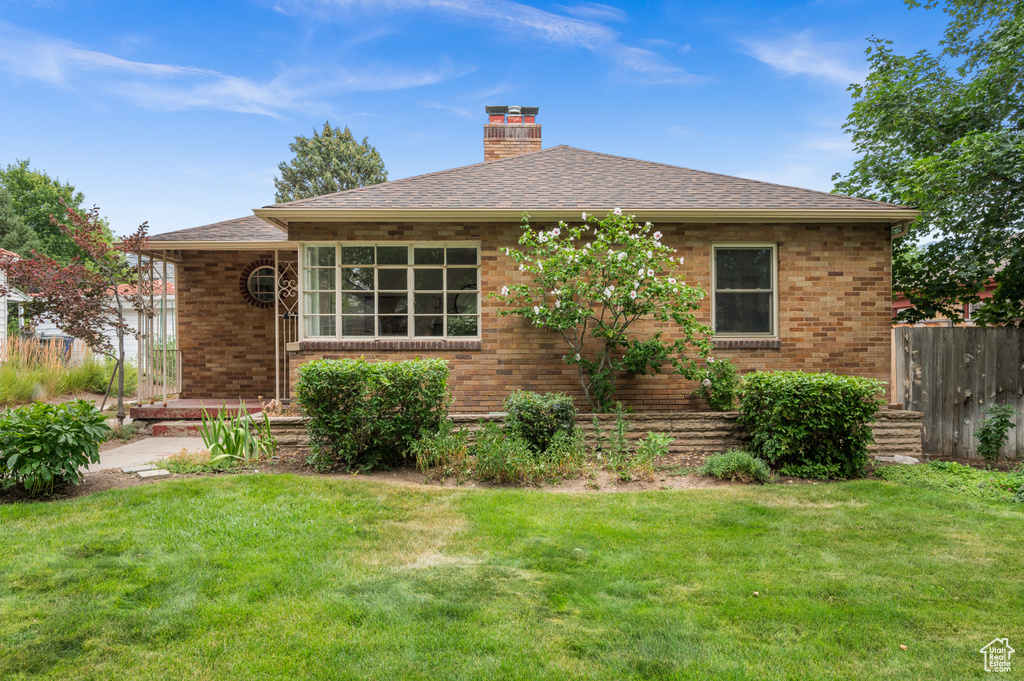 Rear view of property featuring brick siding, a chimney, and roof with shingles