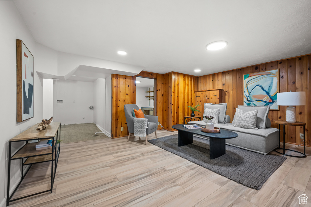 Living area with light wood-type flooring, wooden walls, and recessed lighting