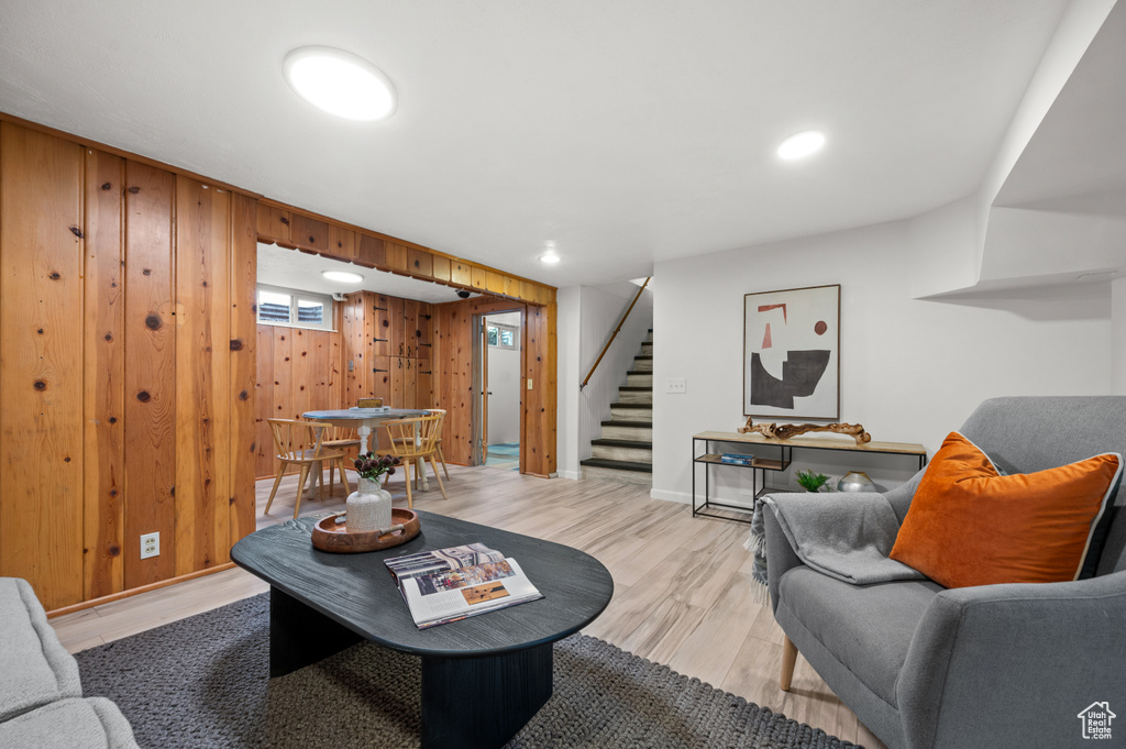 Living room featuring light wood finished floors, stairway, wood walls, and recessed lighting