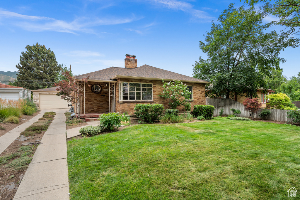 View of front of home with a chimney, brick siding, and roof with shingles