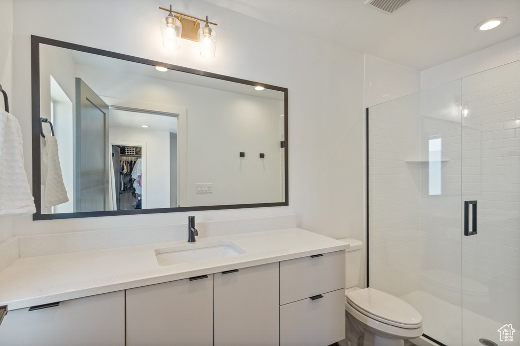 Full bath with vanity, a shower stall, a spacious closet, and recessed lighting