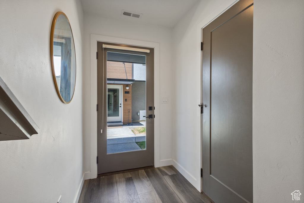 Doorway to outside with dark wood-type flooring and baseboards