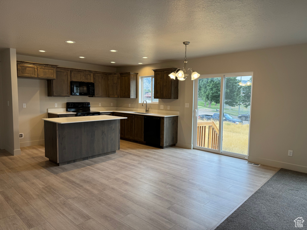 Kitchen featuring light countertops, a chandelier, black appliances, healthy amount of natural light, and recessed lighting