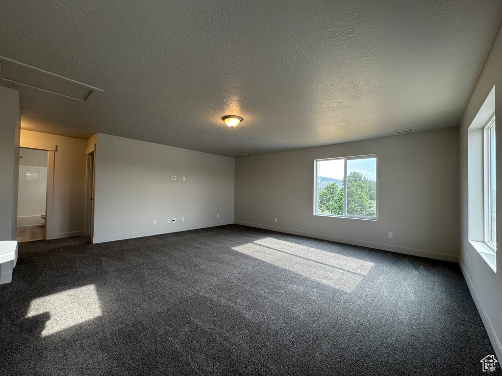Unfurnished room featuring dark colored carpet and a textured ceiling
