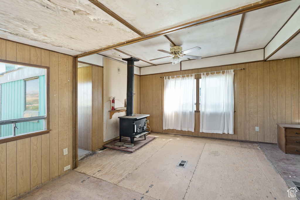 Living room with a wood stove, a ceiling fan, and wood walls