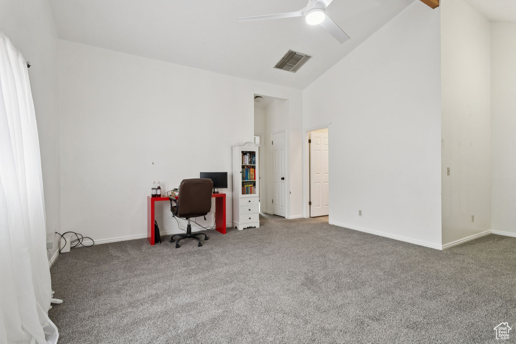 Carpeted home office with ceiling fan and high vaulted ceiling