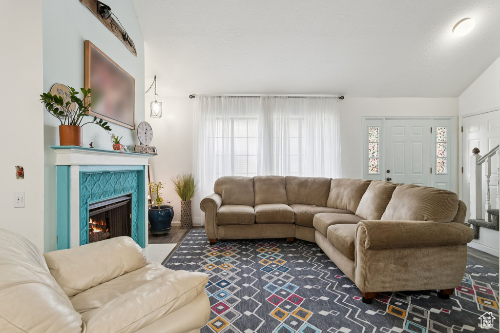 Living area with healthy amount of natural light, a tile fireplace, and vaulted ceiling