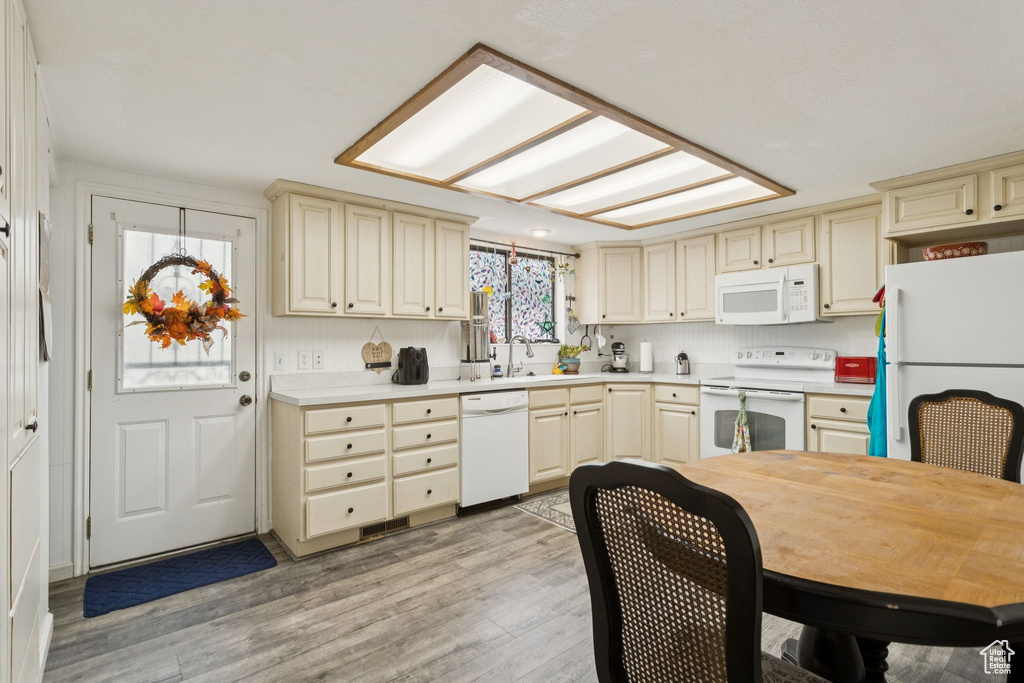 Kitchen featuring cream cabinets, white appliances, light wood-style floors, and light countertops