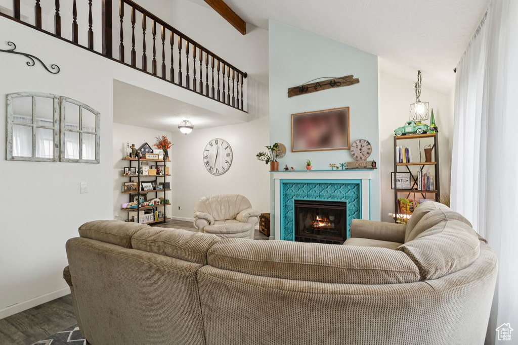Living area with vaulted ceiling, dark wood-style floors, and a tiled fireplace