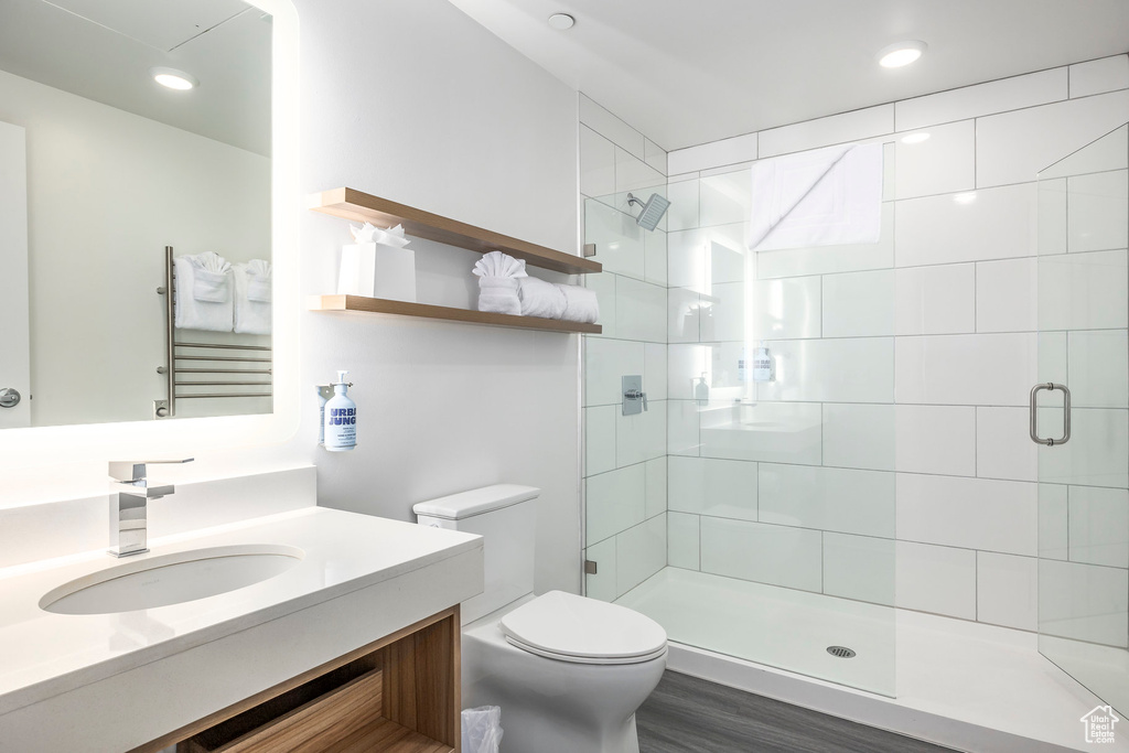 Bathroom featuring a stall shower, vanity, recessed lighting, and wood finished floors