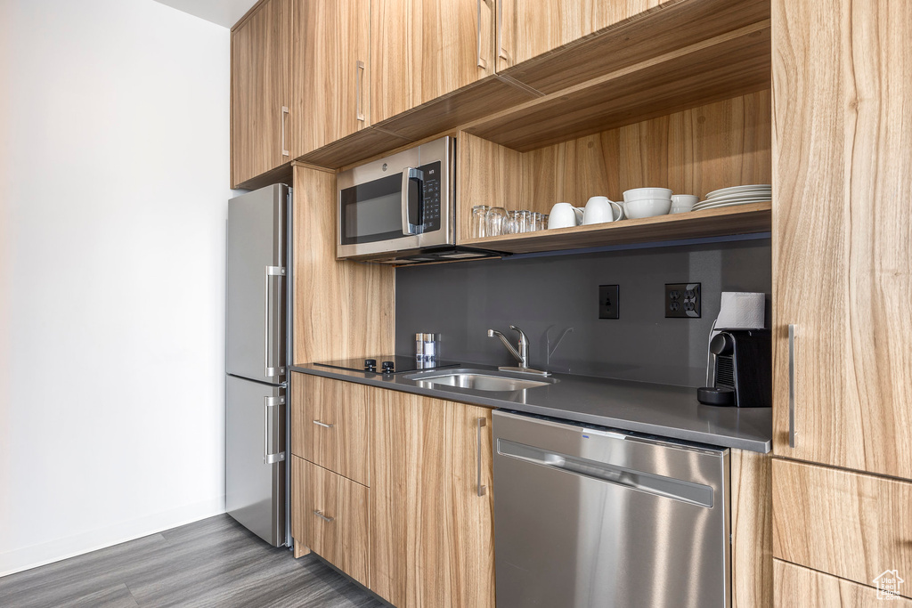 Kitchen with modern cabinets, appliances with stainless steel finishes, dark wood-type flooring, and open shelves