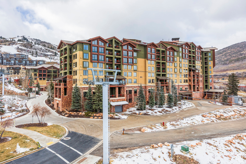 Snow covered building featuring a mountain view and a view of apartment building / complex