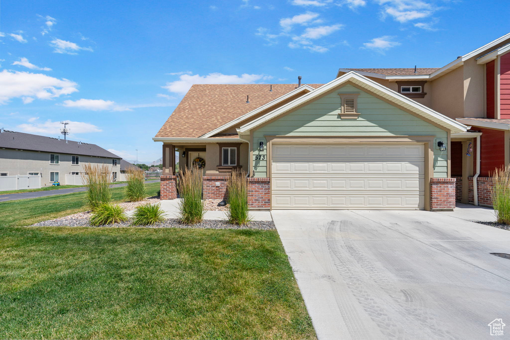 View of front of property with brick siding, an attached garage, a front yard, and concrete driveway