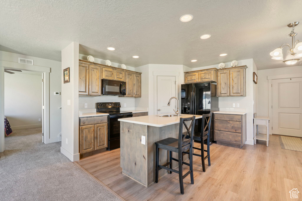 Kitchen featuring black appliances, a kitchen bar, recessed lighting, light countertops, and a chandelier