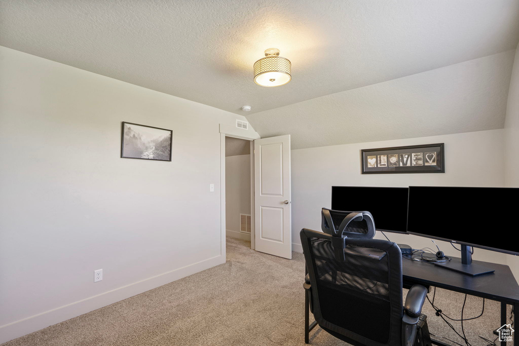 Office with light colored carpet and lofted ceiling