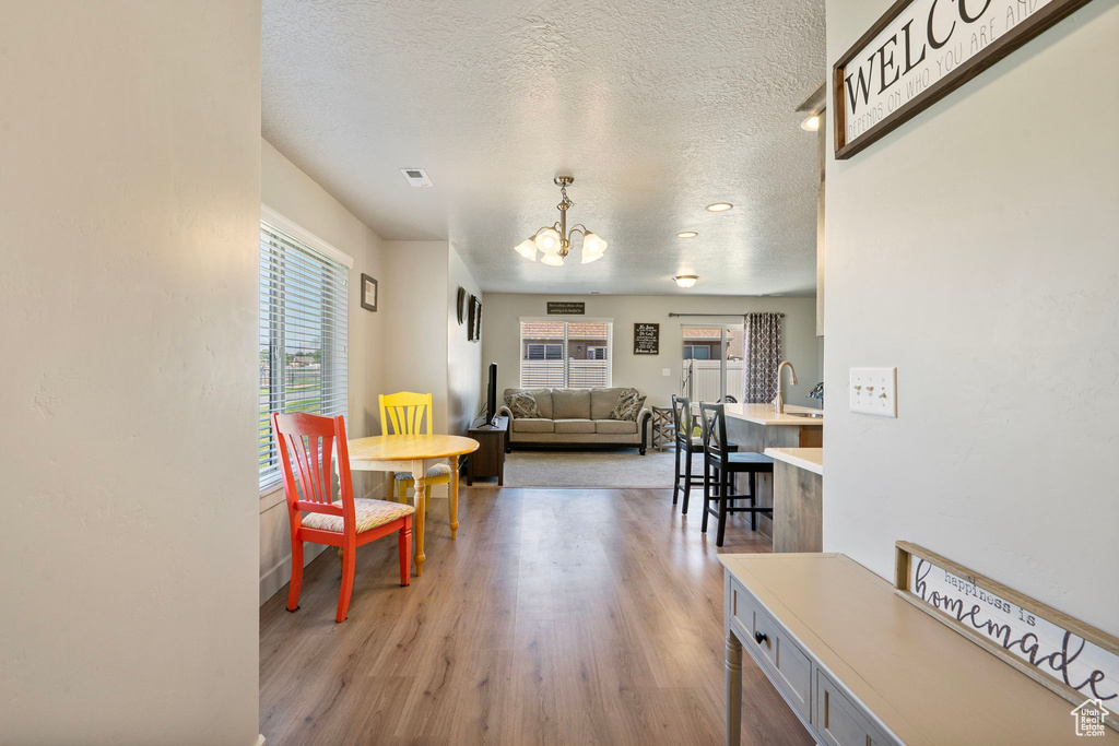 Living room featuring a chandelier, a textured ceiling, and light wood finished floors