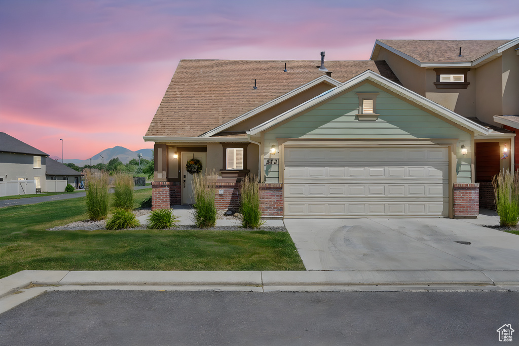 Traditional-style home with brick siding, driveway, a garage, and a yard