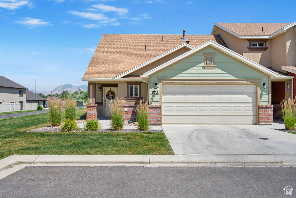 View of front facade with brick siding, an attached garage, driveway, and a mountain view