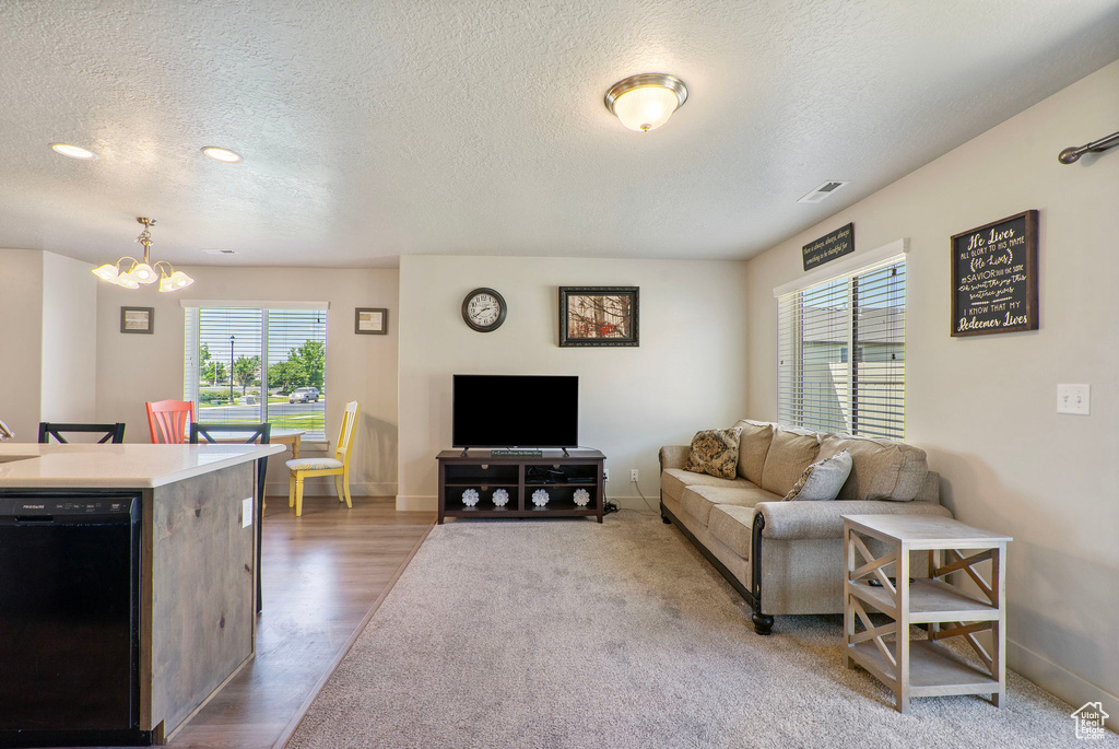 Living area with a chandelier, a textured ceiling, and wood finished floors