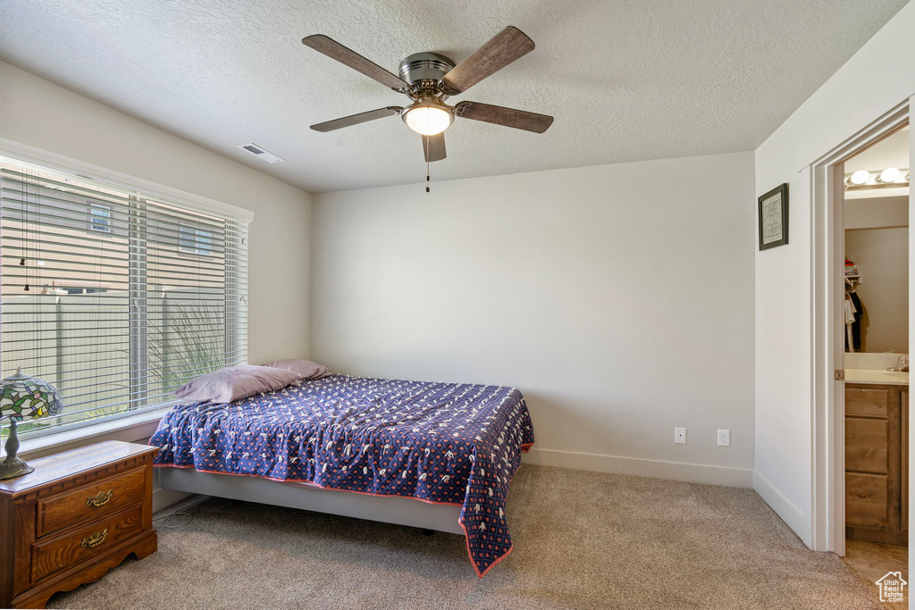 Carpeted bedroom featuring a textured ceiling, a ceiling fan, and connected bathroom