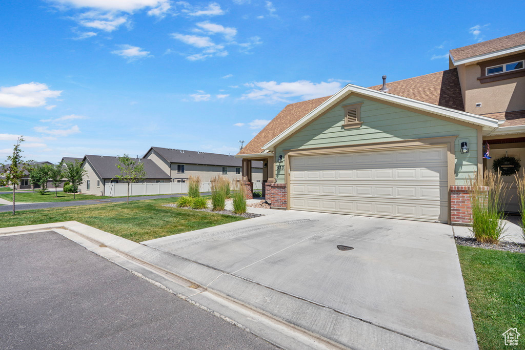 View of front of house with brick siding, concrete driveway, an attached garage, a residential view, and roof with shingles